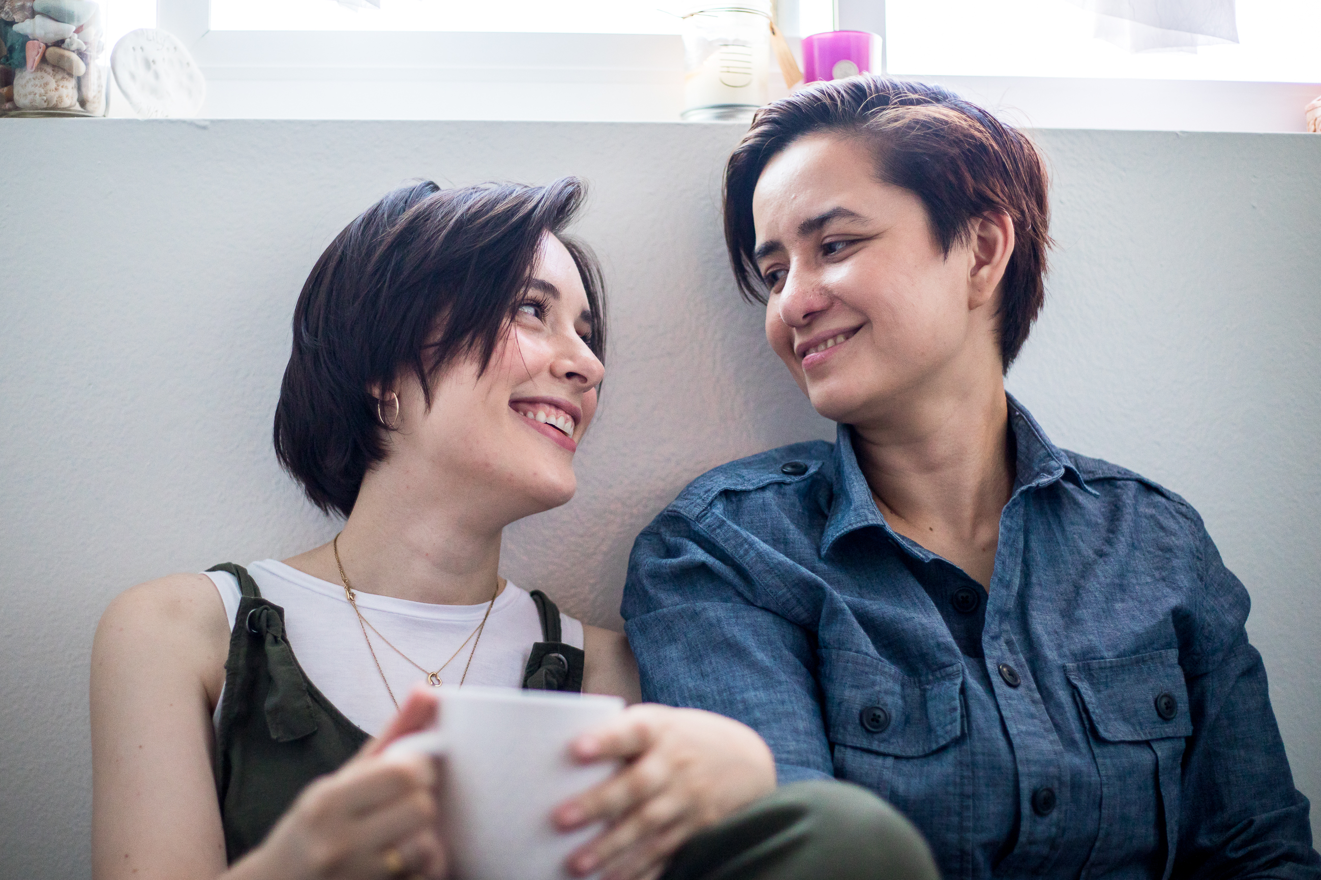 lesbian couple smiling at each other over coffee