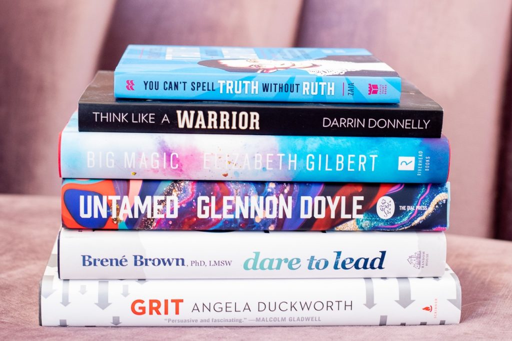 A stack of inspiring books by Brene Brown, Elizabeth Gilbert, Angela Duckworth, Glenon Doyle